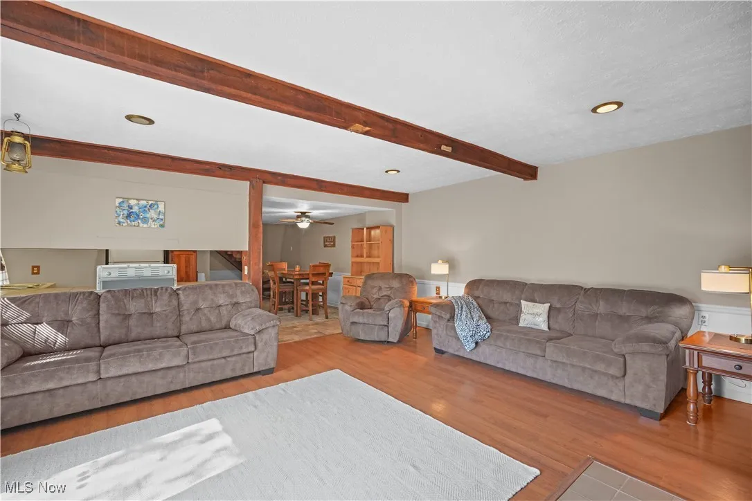 Living area with beamed ceiling, wood finished floors, recessed lighting, and a ceiling fan