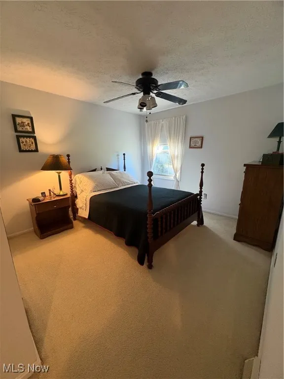 Bedroom featuring light carpet, a textured ceiling, and ceiling fan