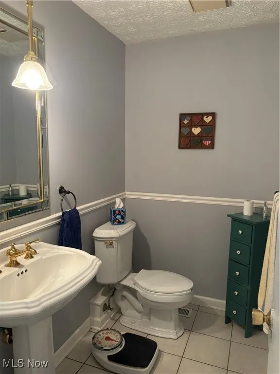 Half bathroom with a textured ceiling and light tile patterned floors