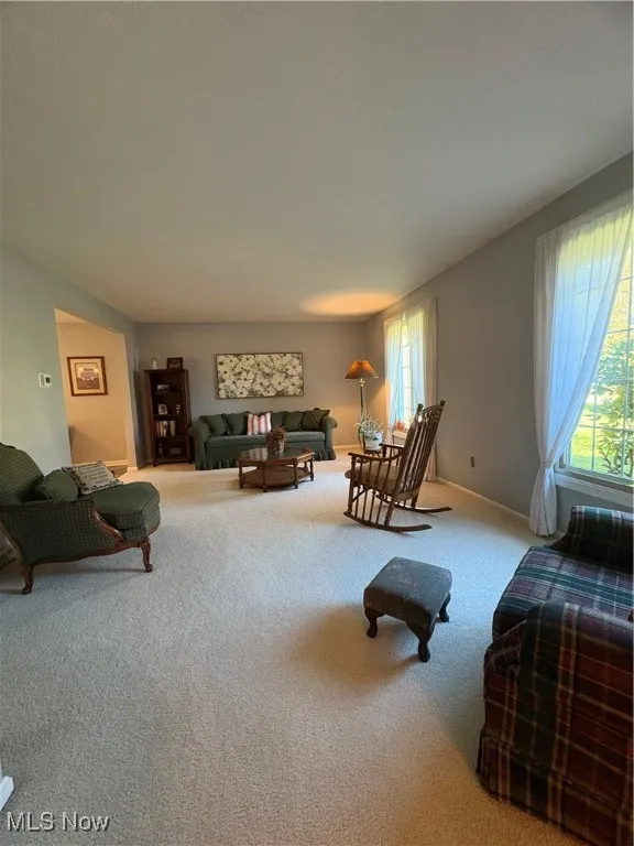 Carpeted living area featuring baseboards