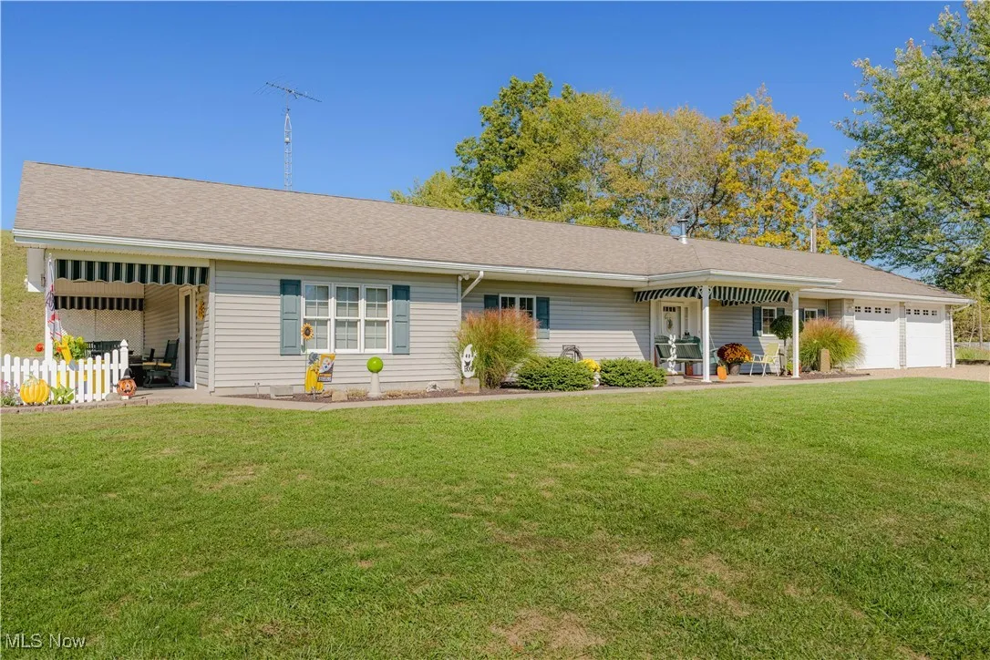Ranch-style house with a front yard, roof with shingles, an attached garage, and a porch