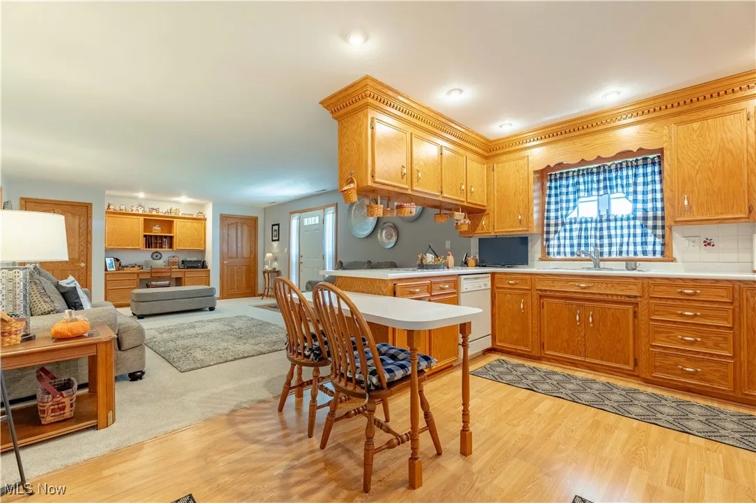 Kitchen with light wood finished floors, light countertops, open floor plan, a peninsula, and dishwasher