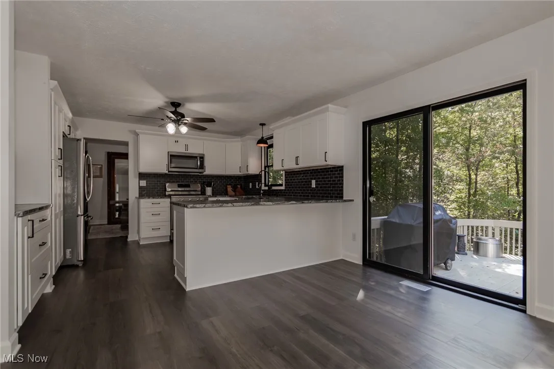 Kitchen with pendant lighting, white cabinets, dark wood finished floors, and a peninsula