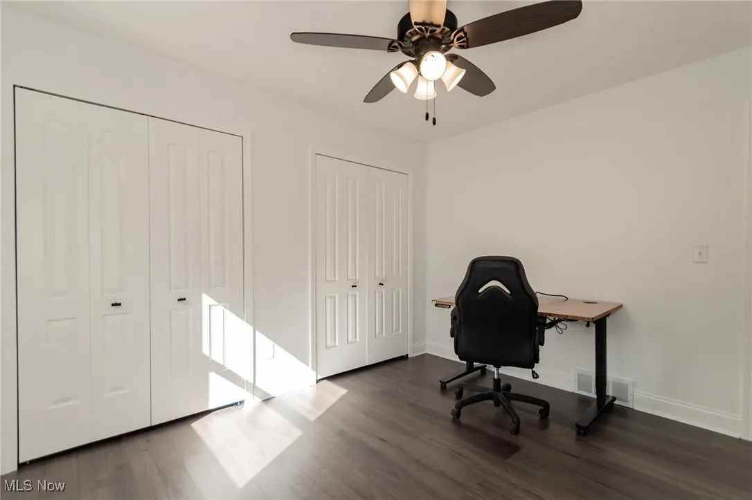 Home office featuring dark wood-type flooring and ceiling fan