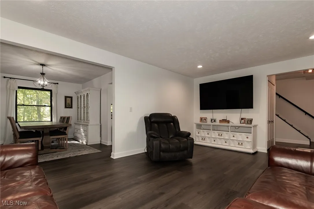 Living area with dark wood-style floors, a chandelier, a textured ceiling, and recessed lighting