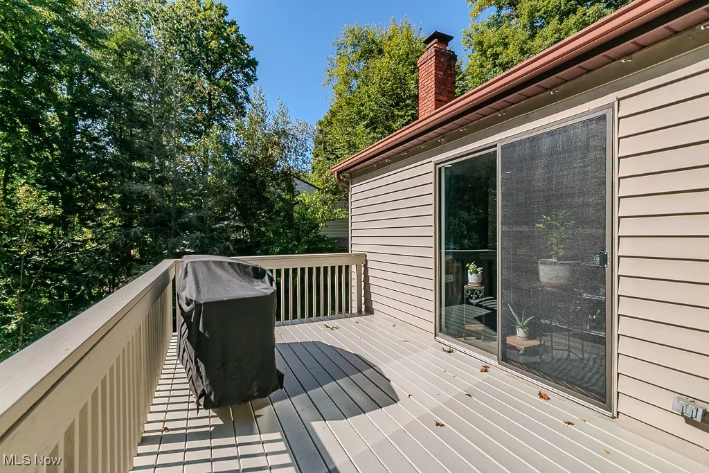 Wooden deck with a grill and view of scattered trees