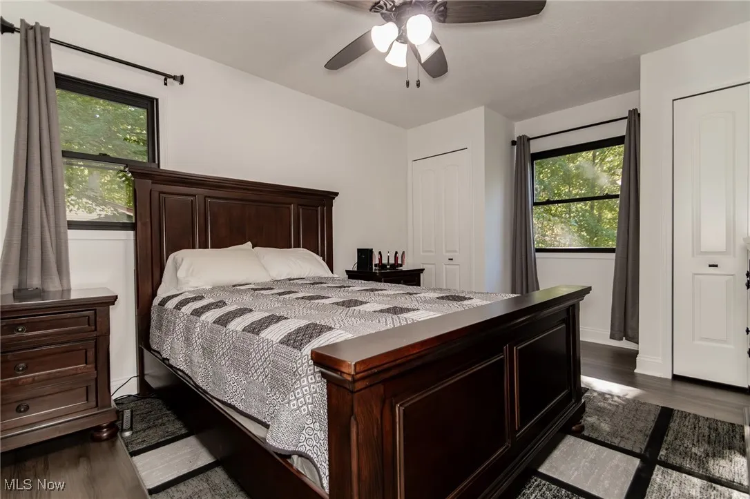 Bedroom featuring dark wood-style floors, two closets, and ceiling fan