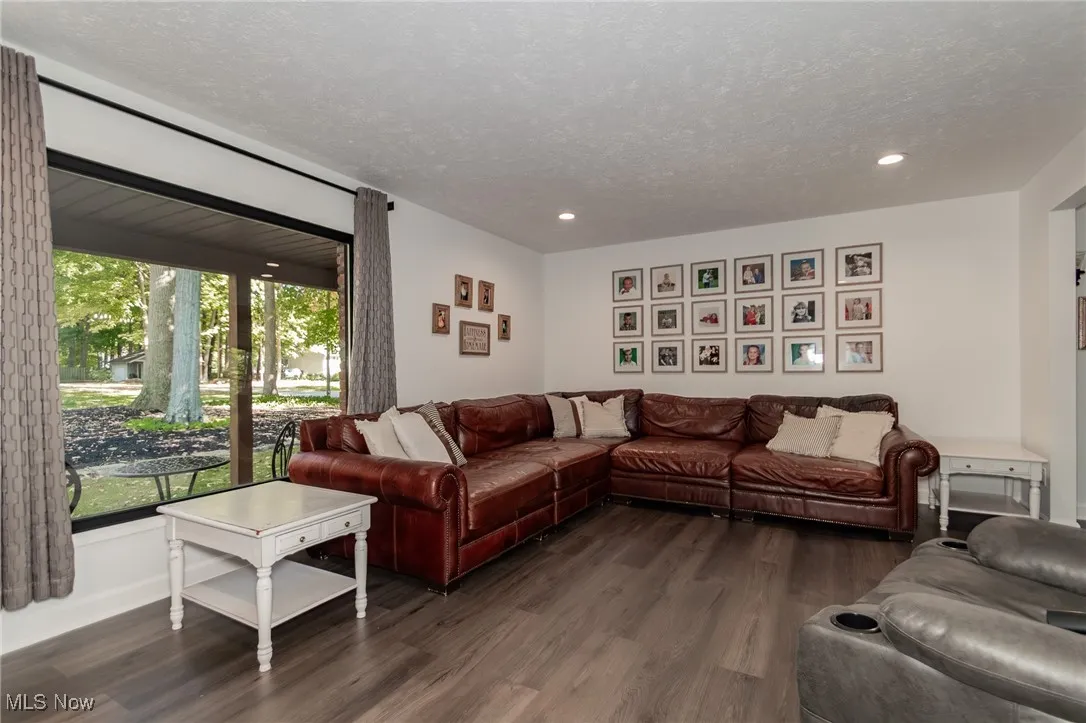 Living room featuring dark wood-style floors, a textured ceiling, and recessed lighting