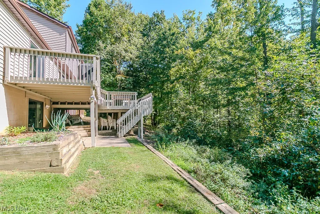 View of grassy yard featuring stairs and a deck