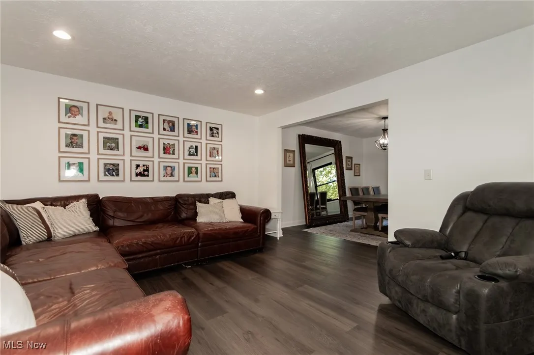 Living area with dark wood-style floors, a textured ceiling, recessed lighting, and a chandelier