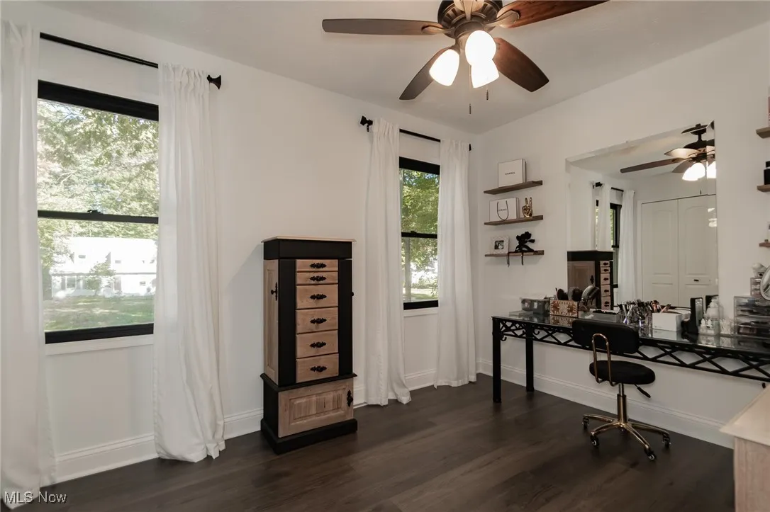 Office area with dark wood-style flooring and ceiling fan