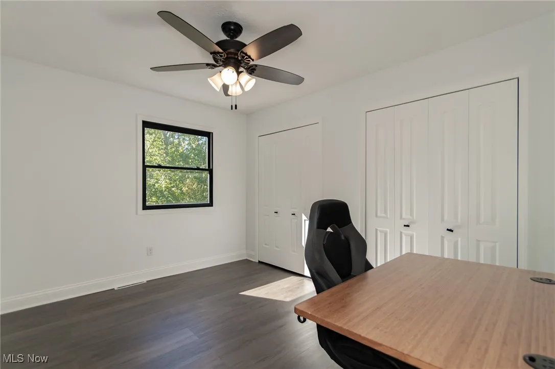 Office space featuring dark wood-type flooring and ceiling fan