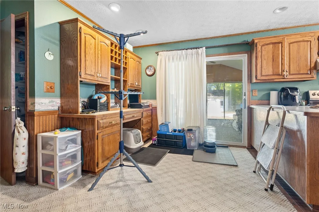 Office space with a textured ceiling, crown molding, and light colored carpet