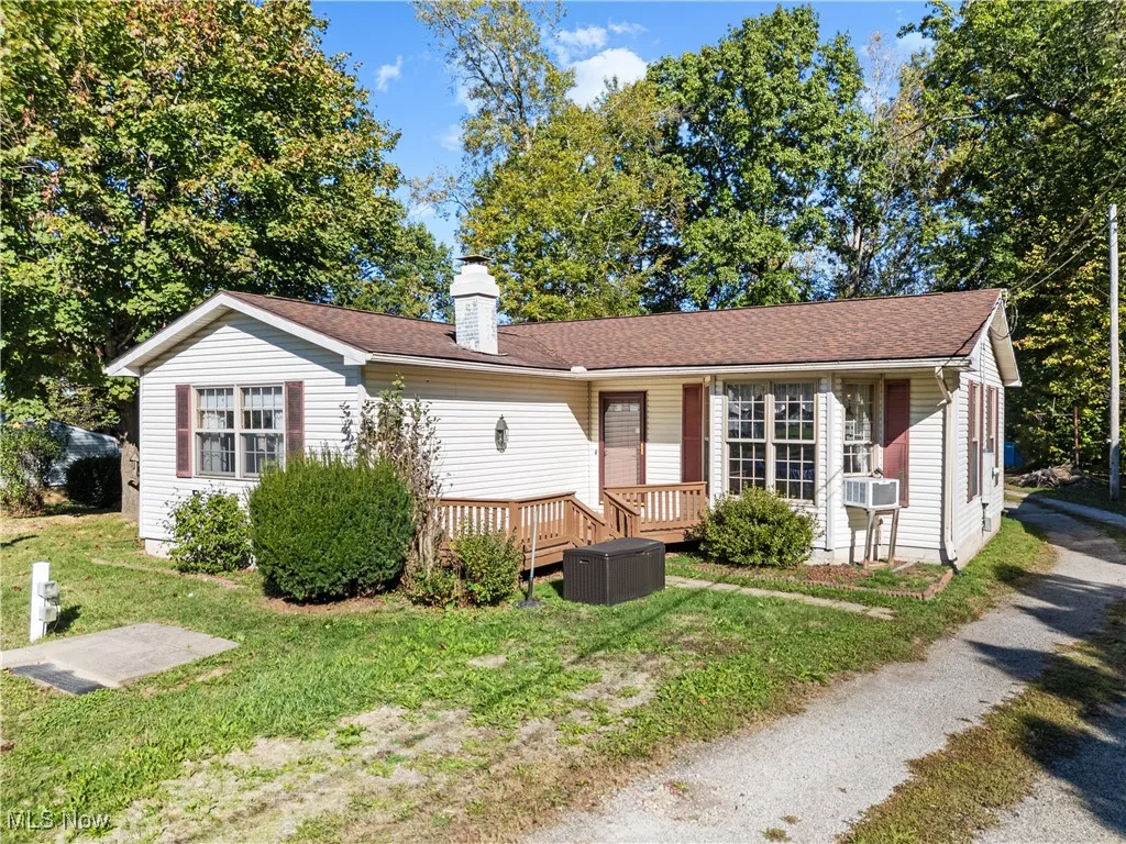 Ranch-style house featuring a chimney, a front lawn, a shingled roof, and a wooden deck
