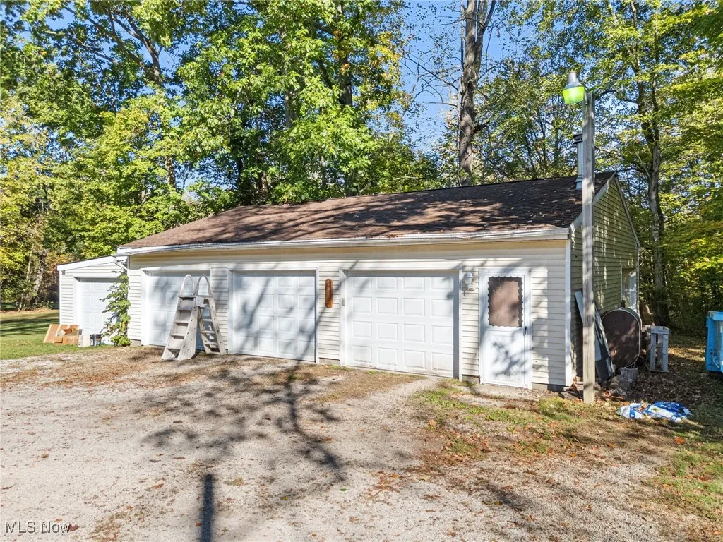 Detached garage featuring view of wooded area