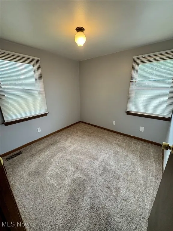 Carpeted spare room featuring baseboards