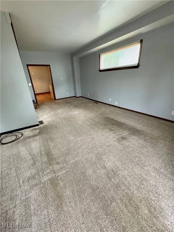Carpeted empty room featuring baseboards