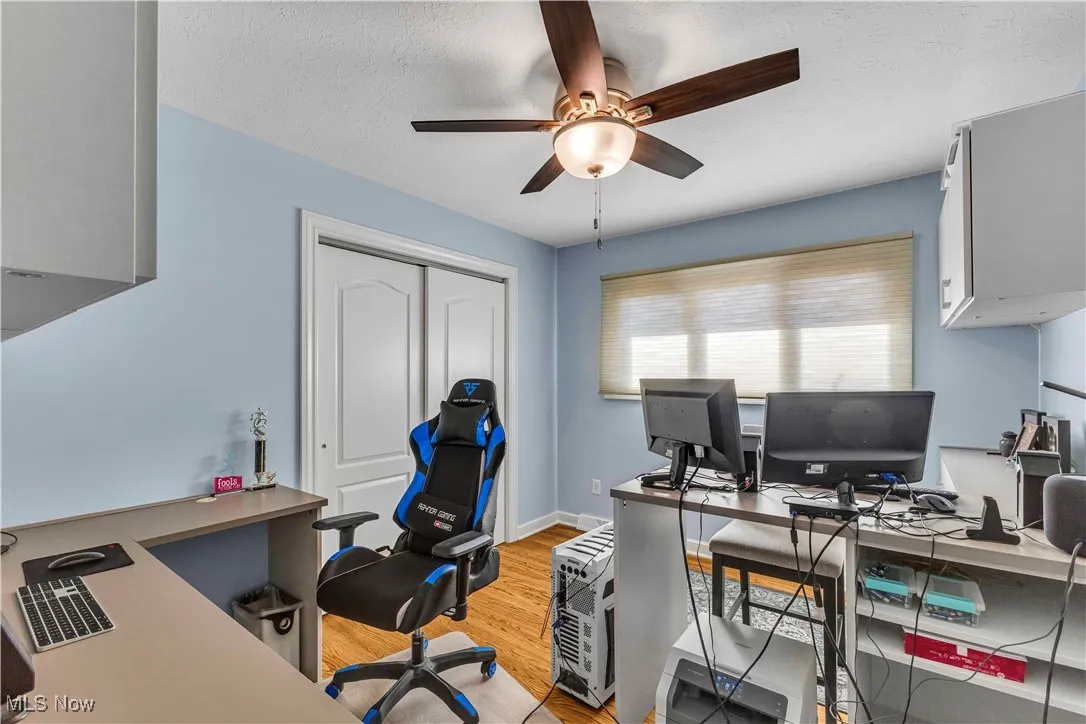 Office space featuring light wood-style floors, a textured ceiling, and ceiling fan