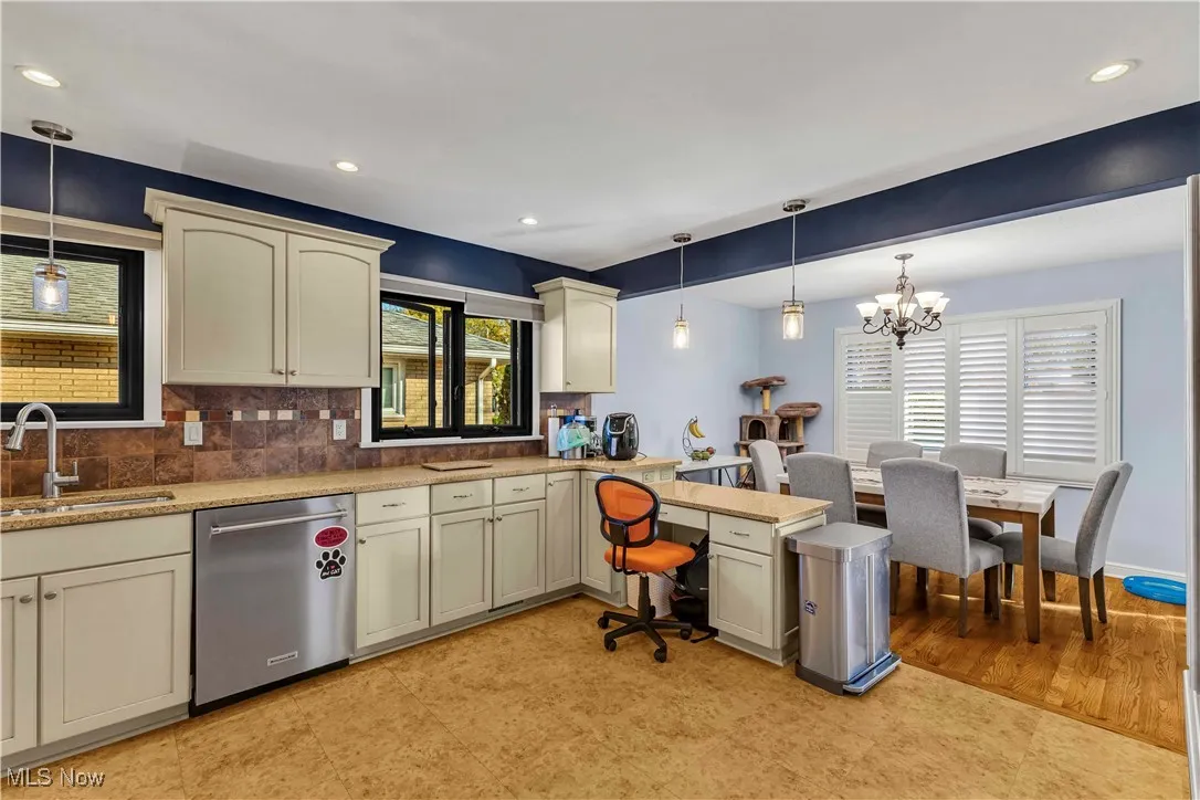 Kitchen featuring decorative light fixtures, a peninsula, cream cabinets, decorative backsplash, and dishwasher