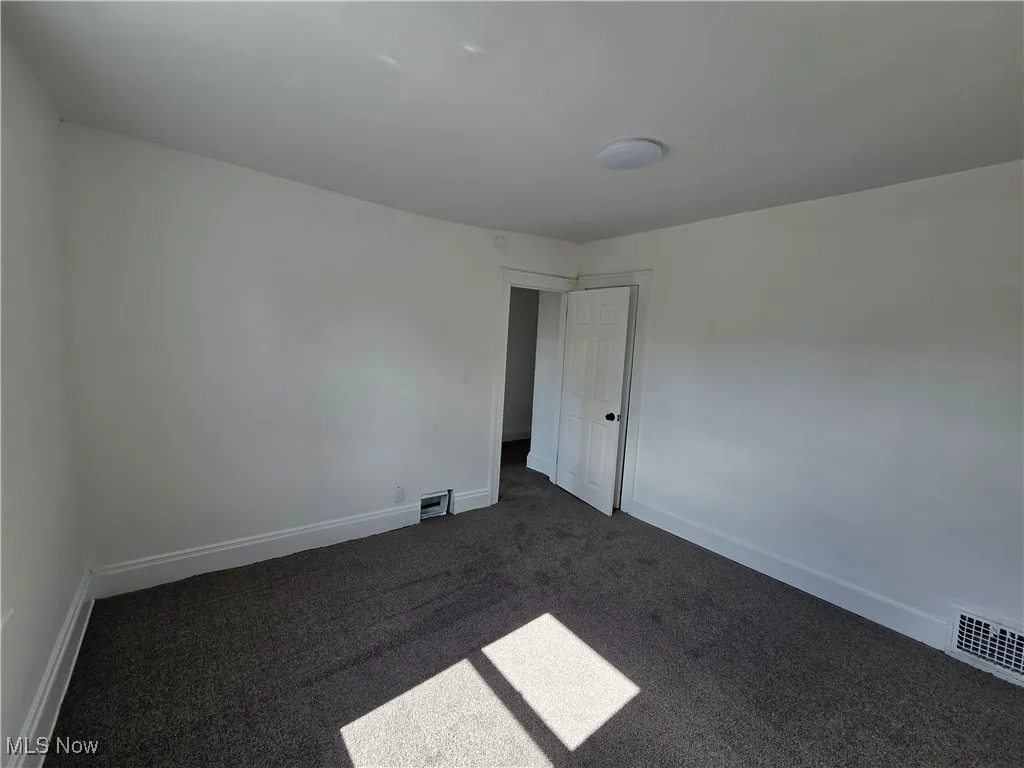 Spare room featuring carpet and baseboards