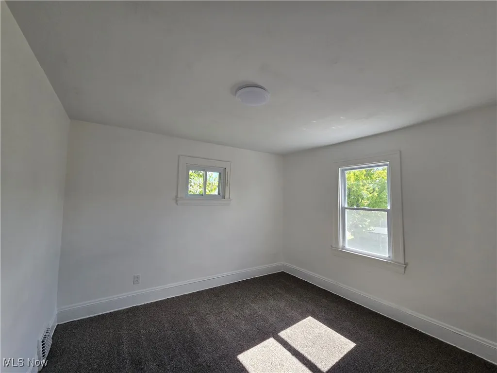 Spare room with dark colored carpet and baseboards