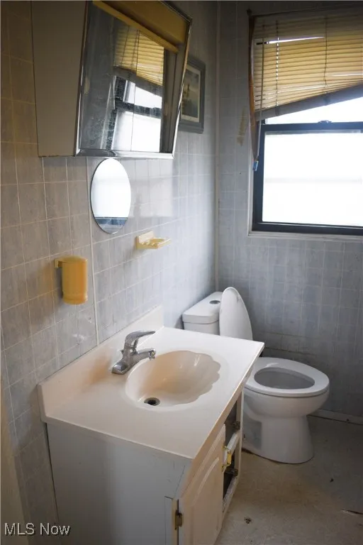 Half bath featuring vanity, tile walls, and light tile patterned floors