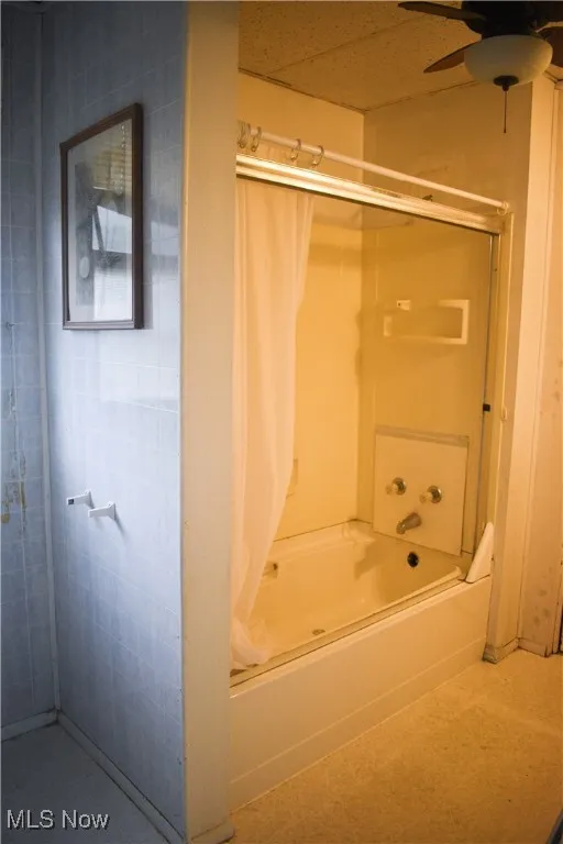 Bathroom featuring shower / bathtub combination with curtain and a ceiling fan