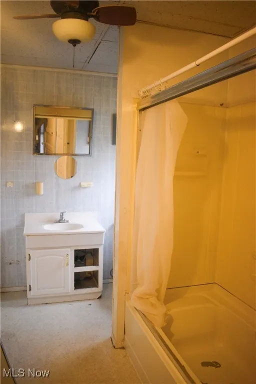 Bathroom featuring shower / bath combo, vanity, a ceiling fan, and light flooring