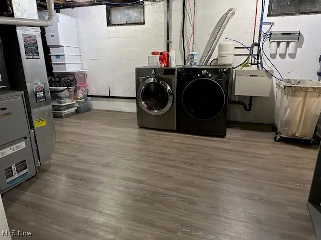 Washroom featuring wood finished floors, heating unit, and separate washer and dryer