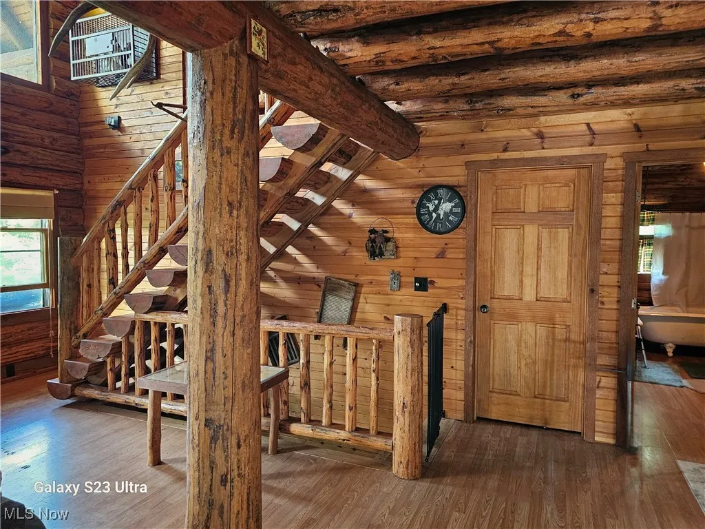Stairway featuring plenty of natural light, wooden walls, and wood finished floors