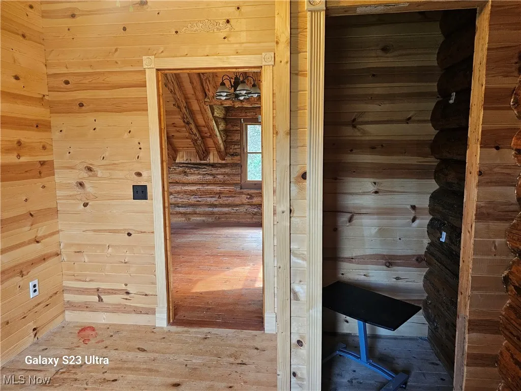 Sauna / steam room with wood-type flooring, wood walls, and rustic walls