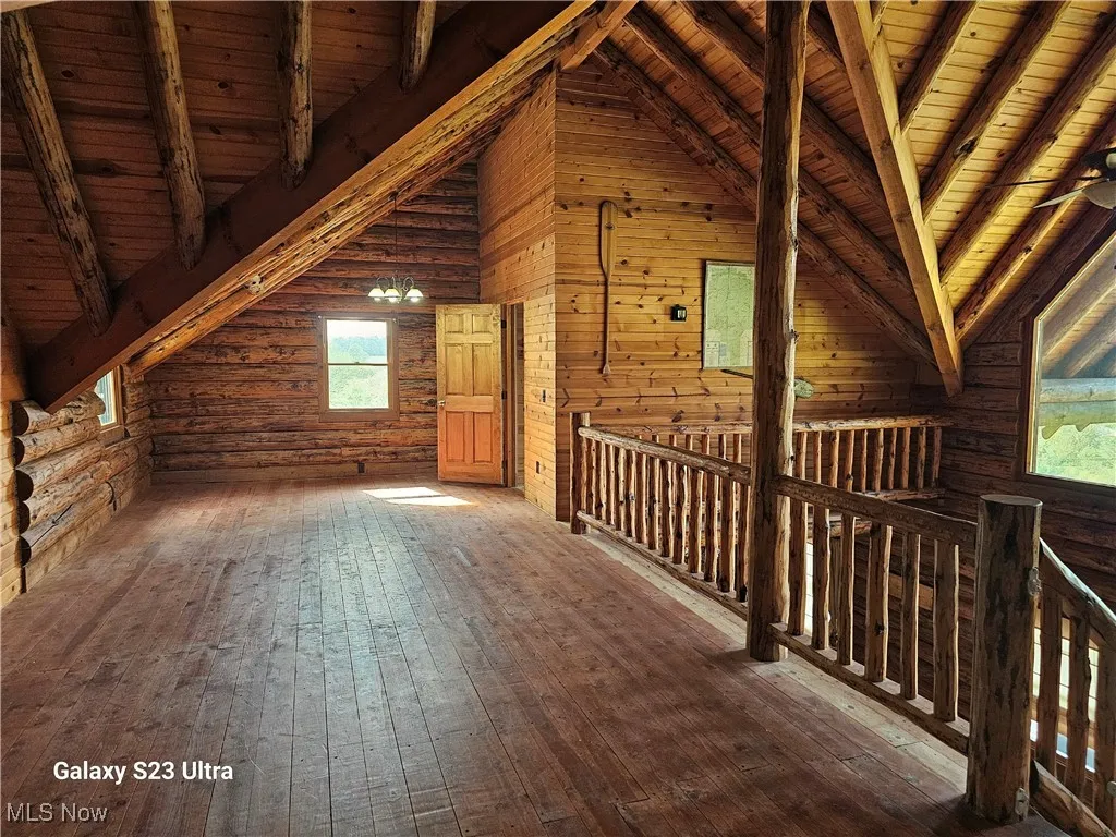 Bonus room with log walls, hardwood / wood-style flooring, a wooden ceiling with exposed beams, and high vaulted ceiling