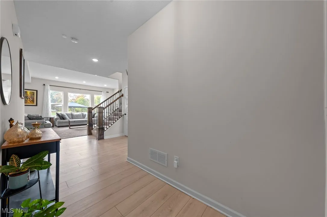 Corridor with stairs, light wood-style flooring, and recessed lighting