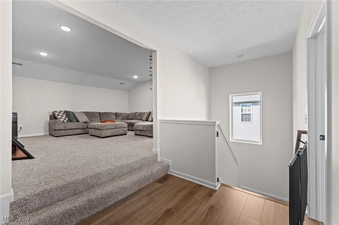 Staircase with wood finished floors, recessed lighting, and a textured ceiling