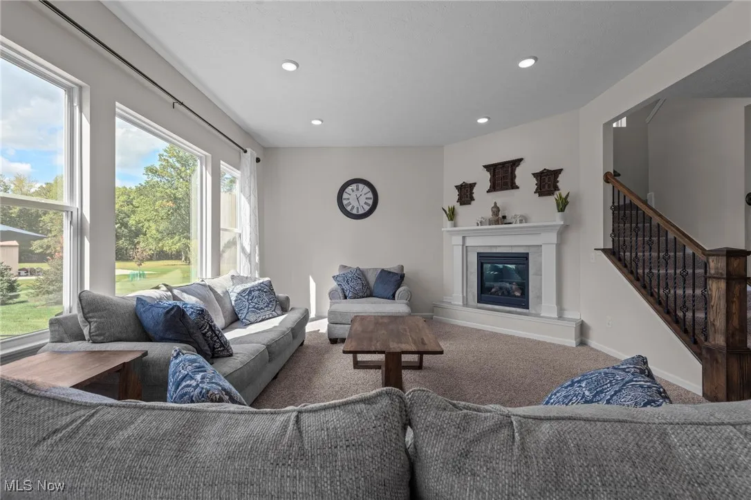 Carpeted living room with a fireplace, recessed lighting, and stairs