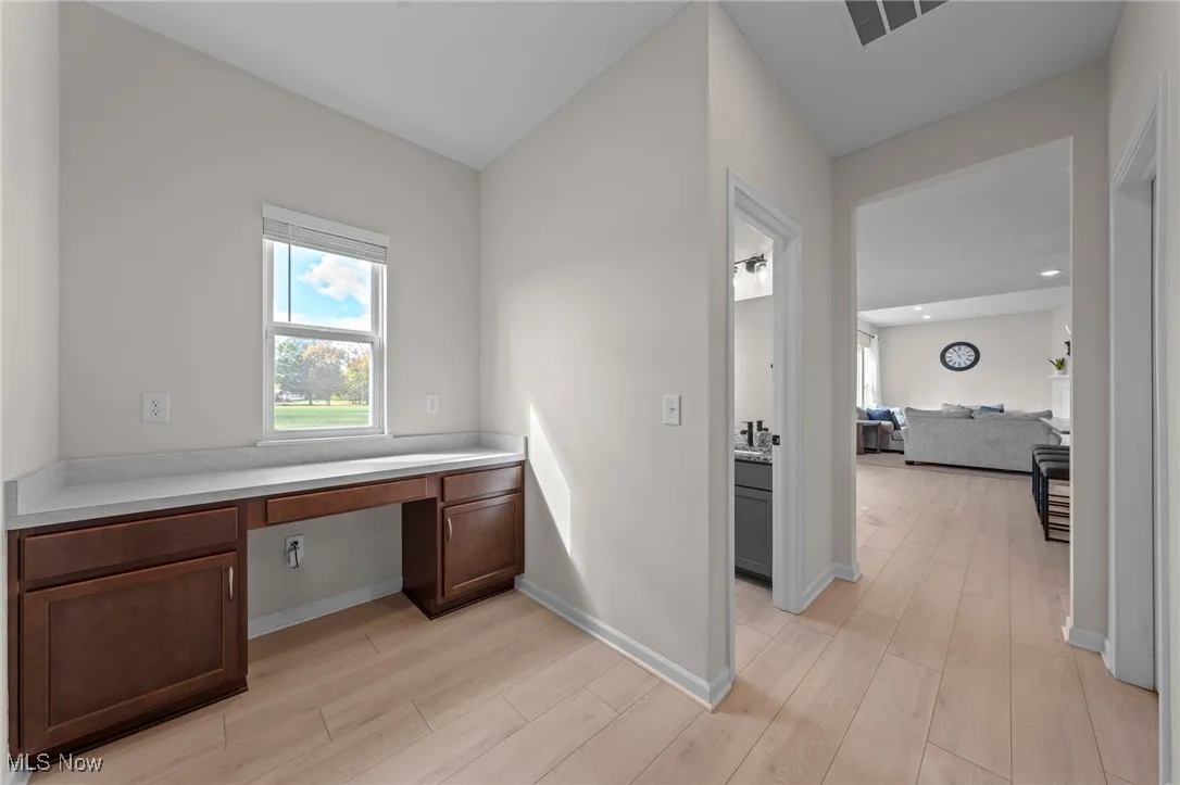 Unfurnished office featuring built in desk and light wood-type flooring