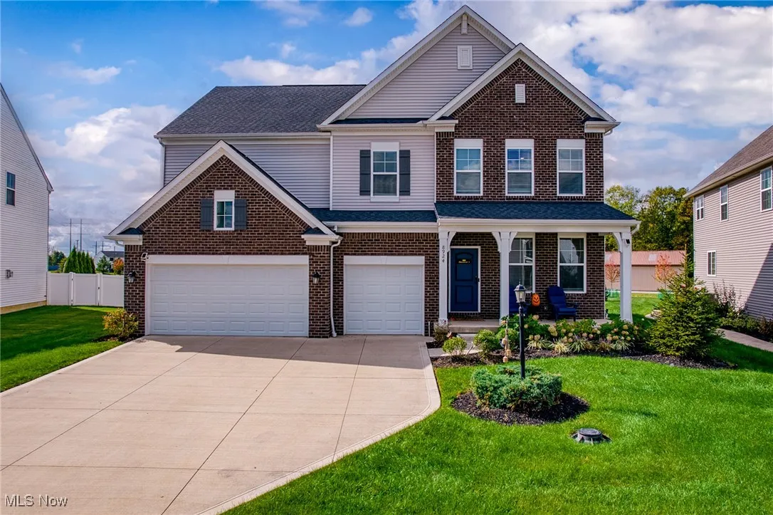 Traditional-style house with covered porch, a garage, brick siding, concrete driveway, and roof with shingles