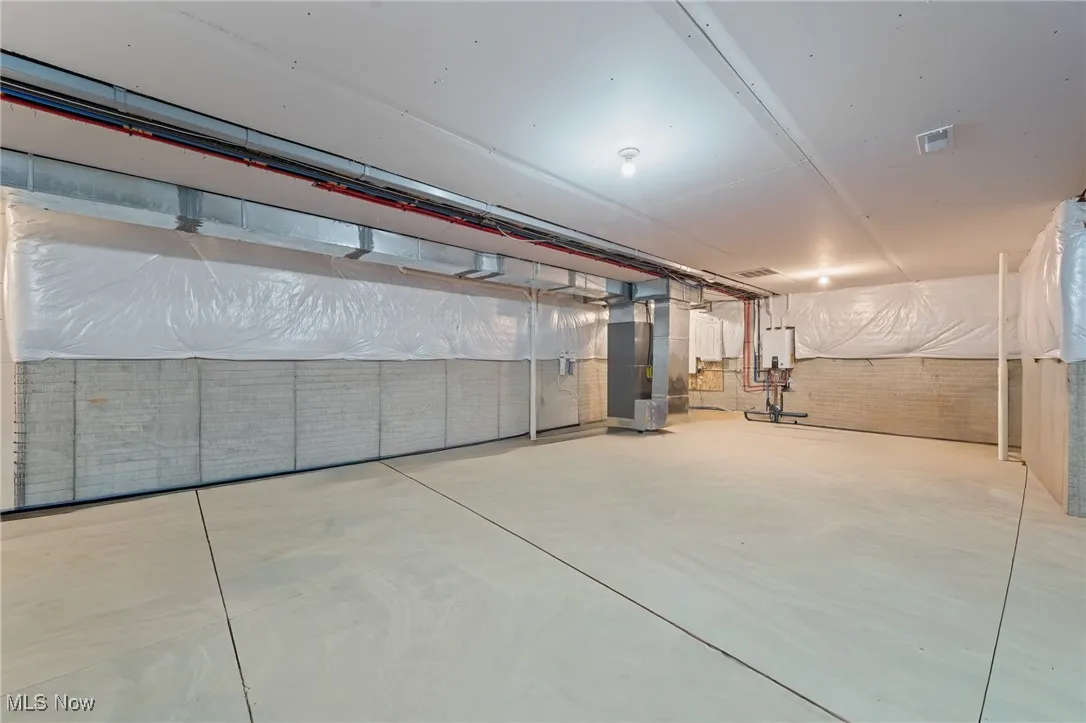 Unfinished below grade area with heating unit and tankless water heater
