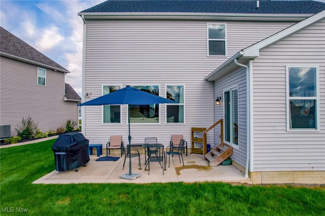 Back of property with a lawn, a patio, and entry steps