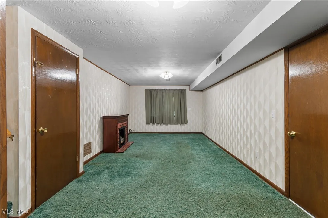 Unfurnished room with carpet floors and a brick fireplace
