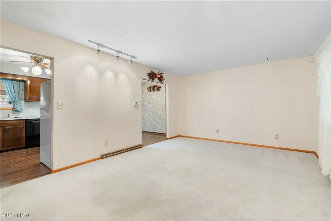 Unfurnished room with carpet floors, a ceiling fan, and wood finished floors