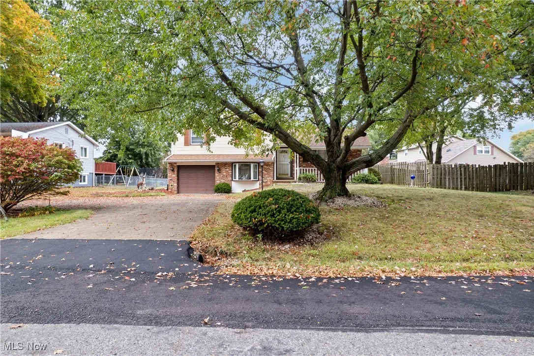 Obstructed view of property with driveway, brick siding, and an attached garage