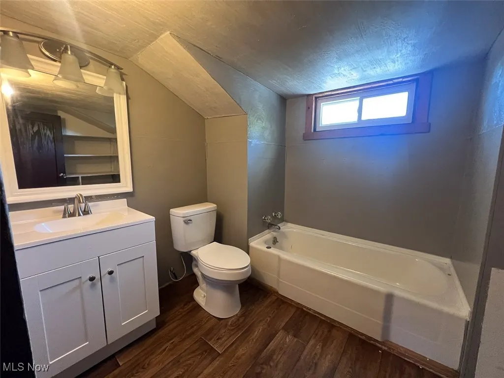 Bathroom with dark wood-style floors, a garden tub, and vanity