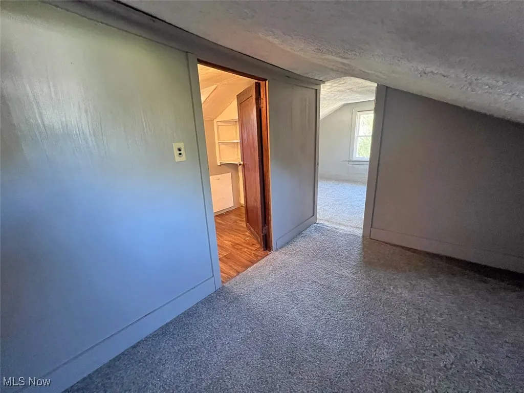 Bedroom with carpet floors, lofted ceiling, and a textured ceiling