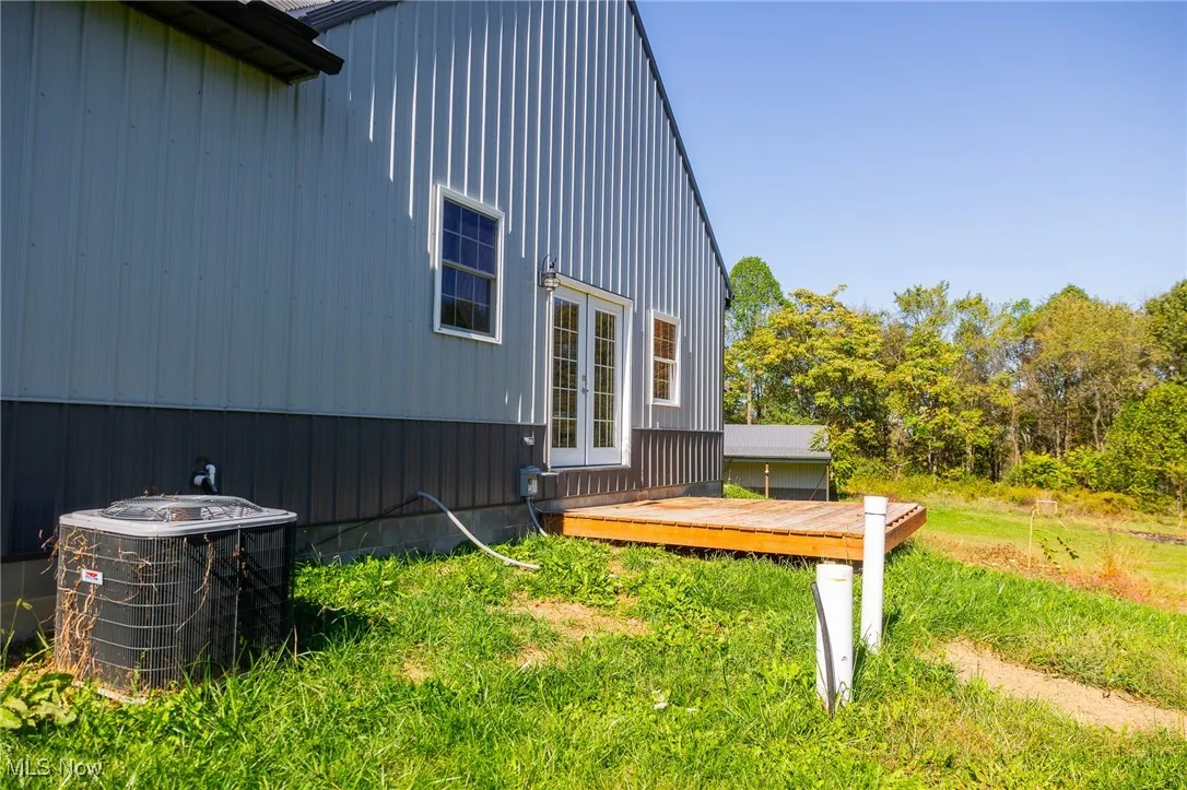 View of side of property featuring a wooden deck, french doors, and a lawn
