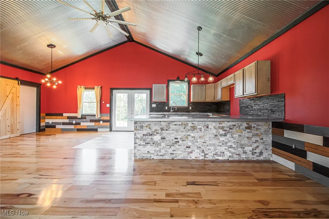 Kitchen featuring light wood-style flooring, open floor plan, pendant lighting, a chandelier, and high vaulted ceiling