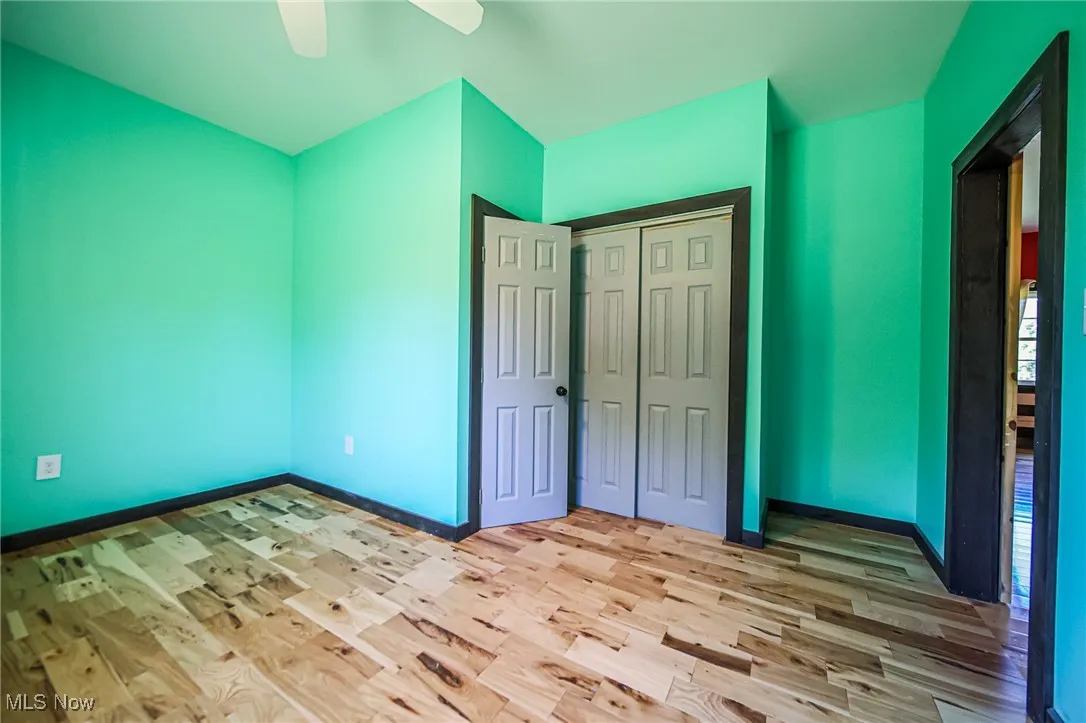Unfurnished bedroom with wood finished floors, a closet, and a ceiling fan