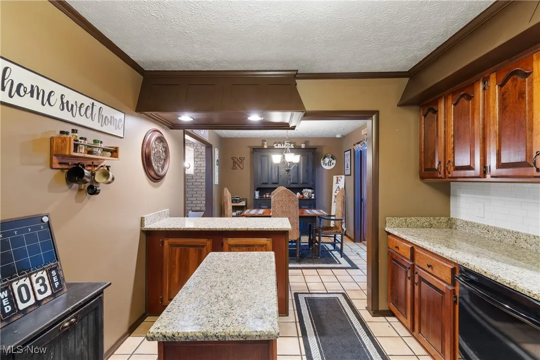 Kitchen with a textured ceiling, dishwasher, backsplash, a peninsula, and crown molding