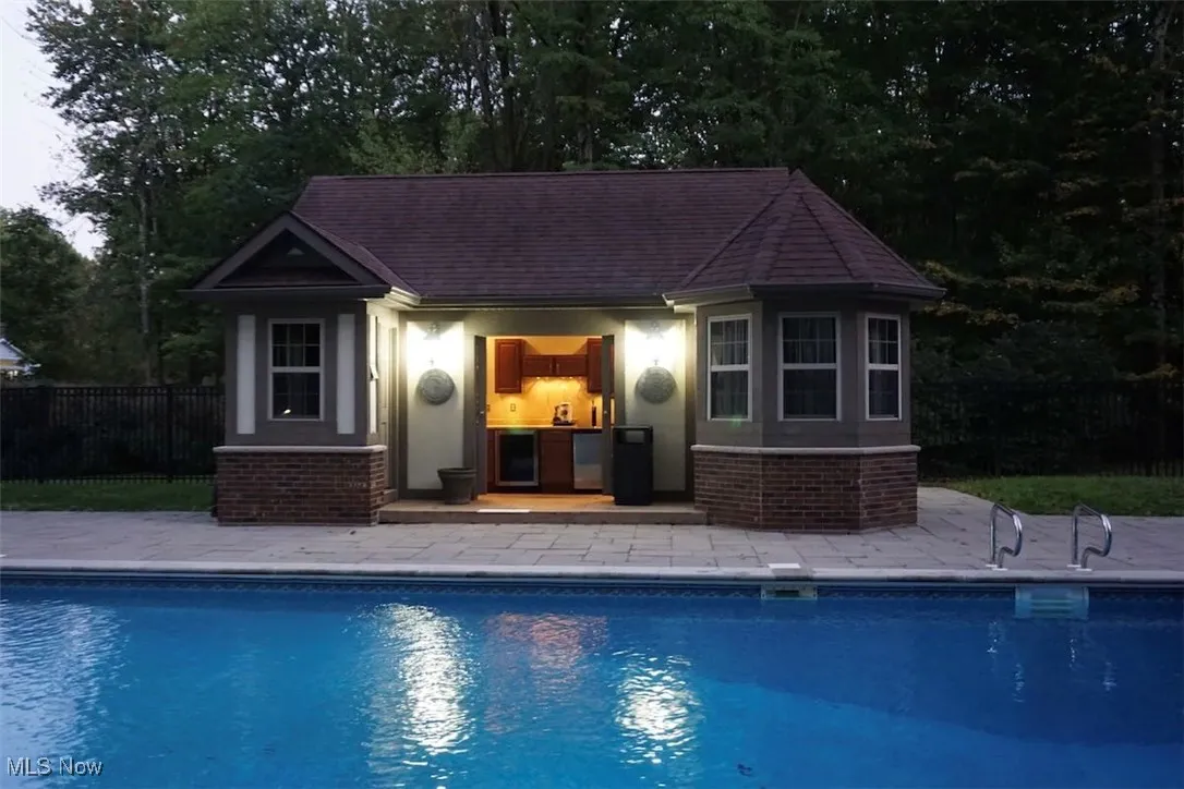 View of swimming pool featuring a cabana with wine refrigerator, keg cooler, refrigerator. Full bathroom and changing area.