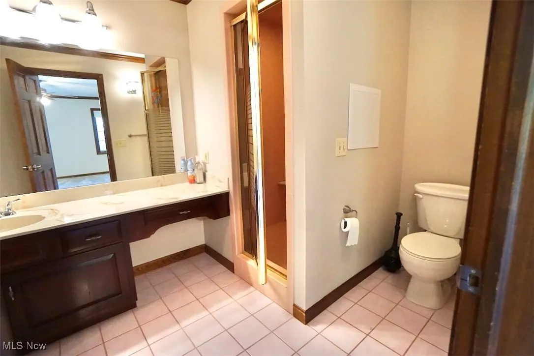 Full bath featuring light tile patterned floors, vanity, and a stall shower